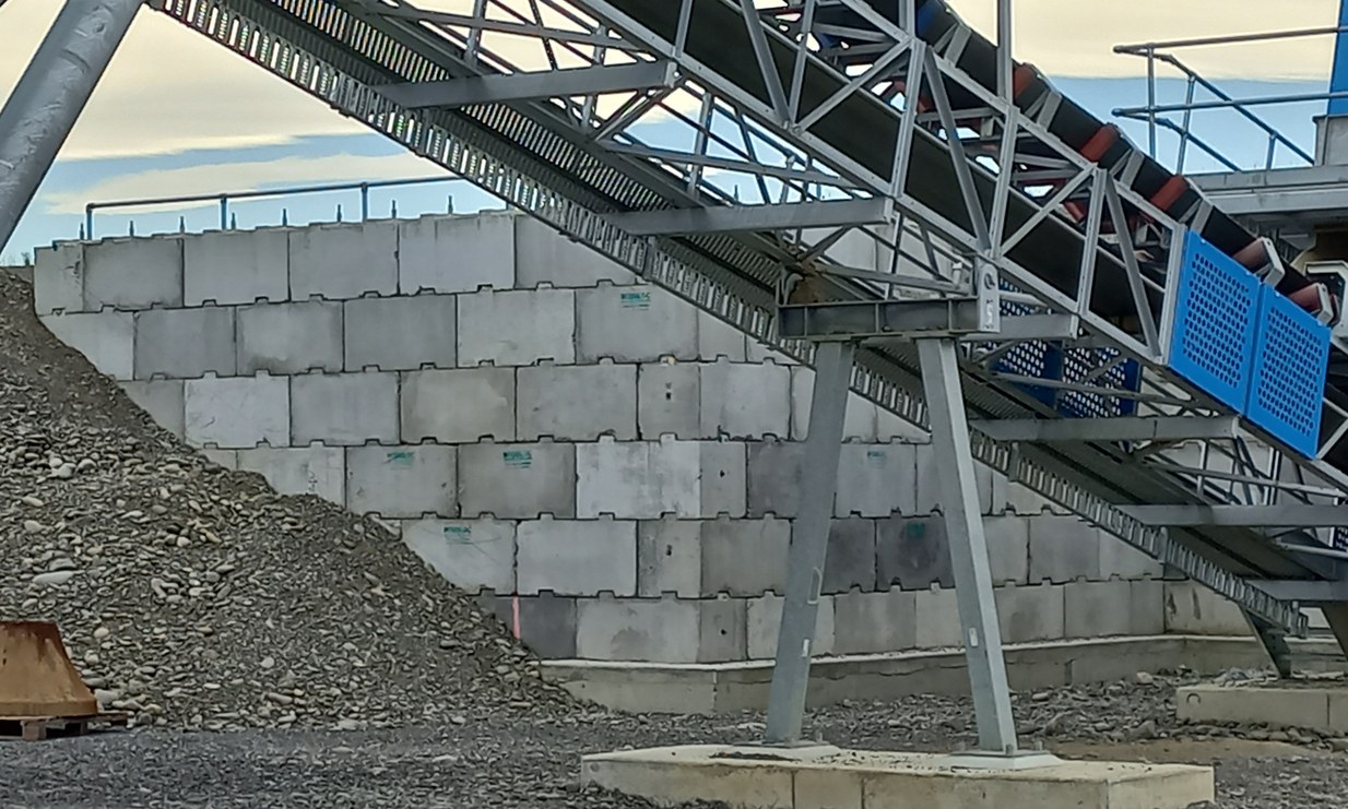 Interbloc retaining wall along a mine haul road beneath a conveyor