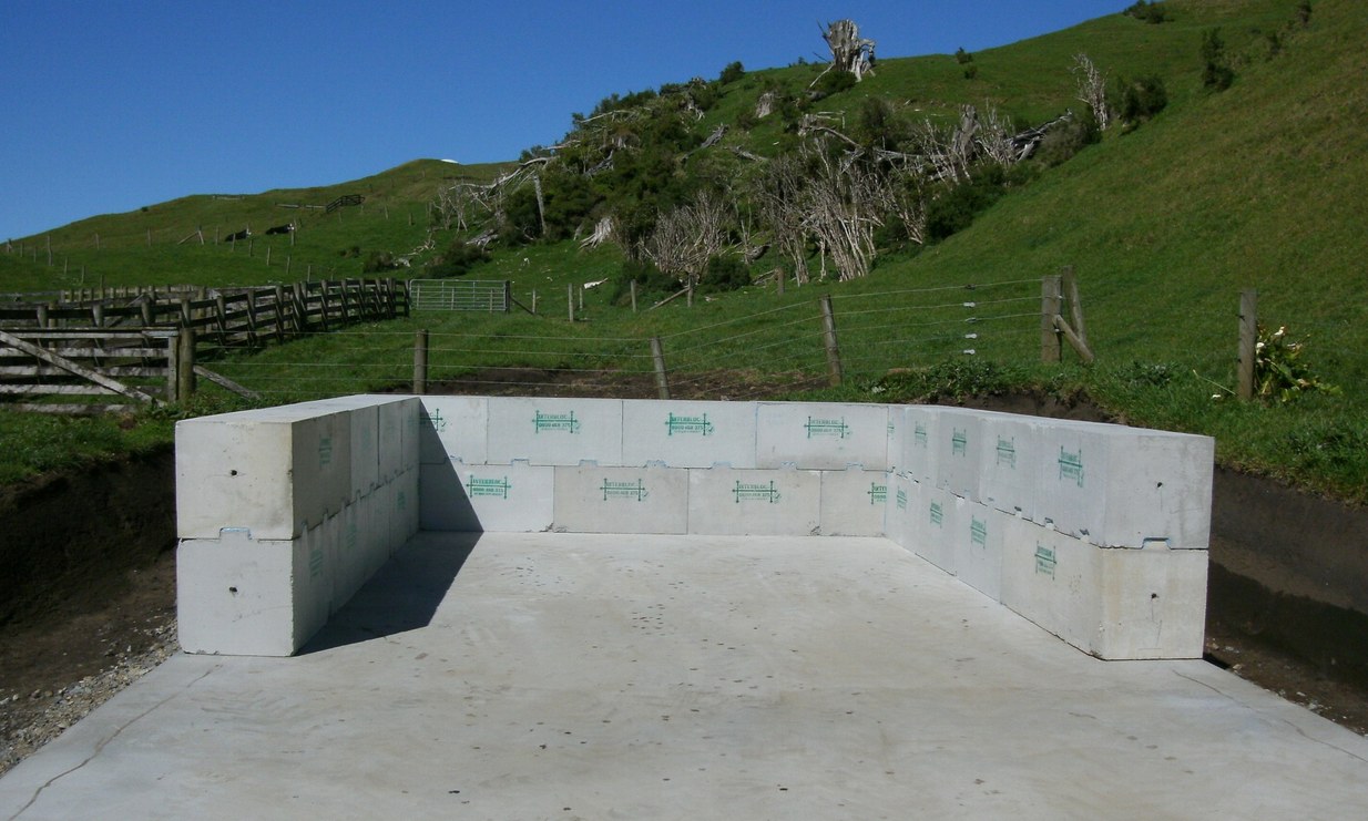 Excavator installing an Interbloc ROM pad retaining wall