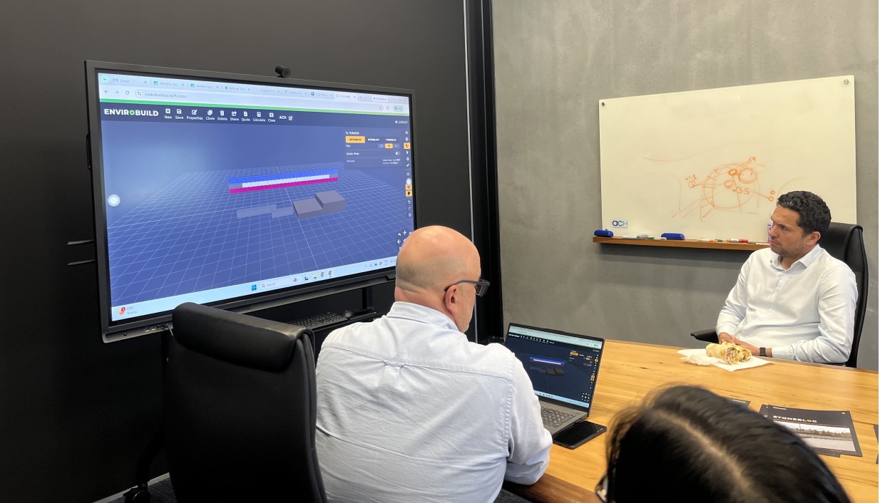 Two colleagues reviewing an Envirobuild design on a large meeting-room screen
