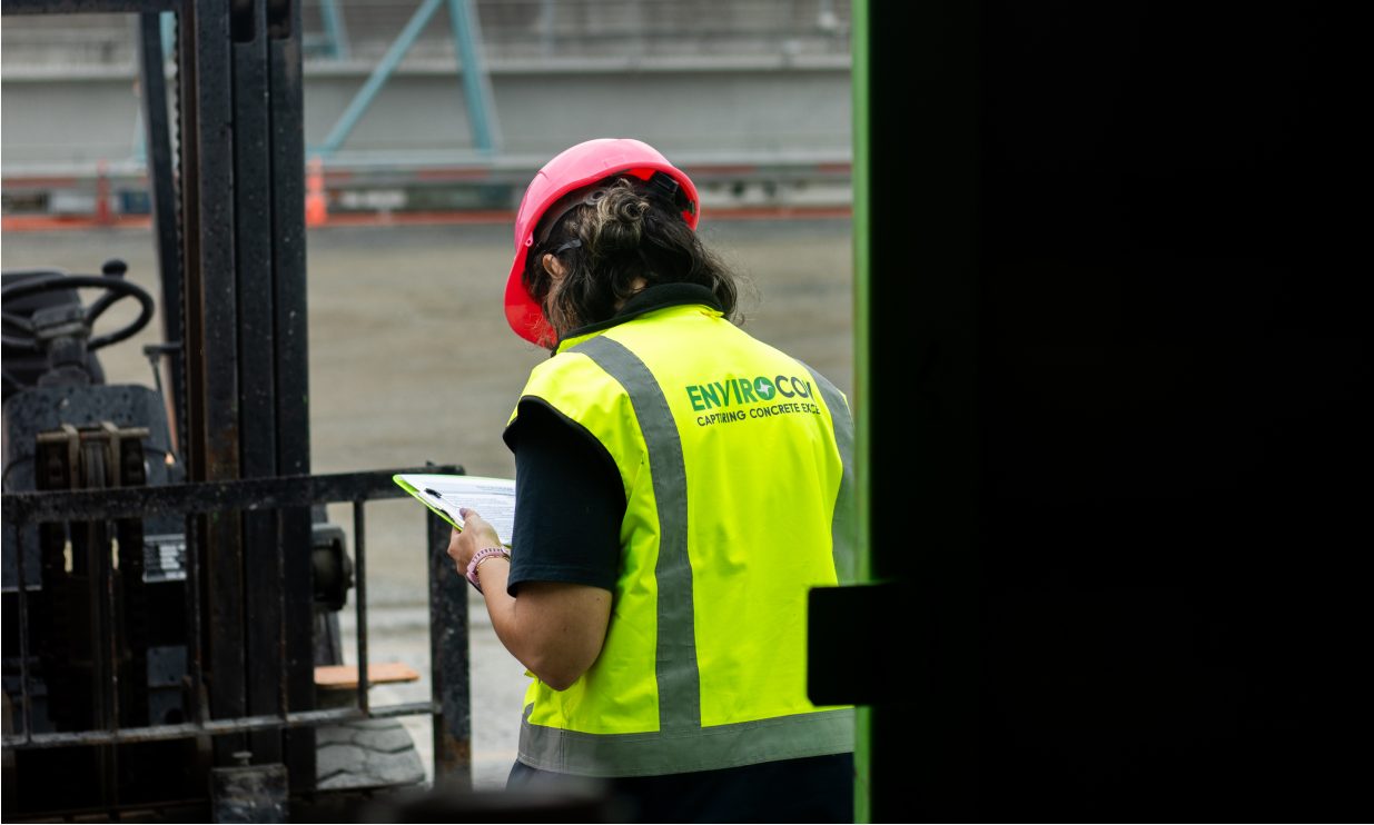 Envirocon site worker reviewing plans with a clipboard