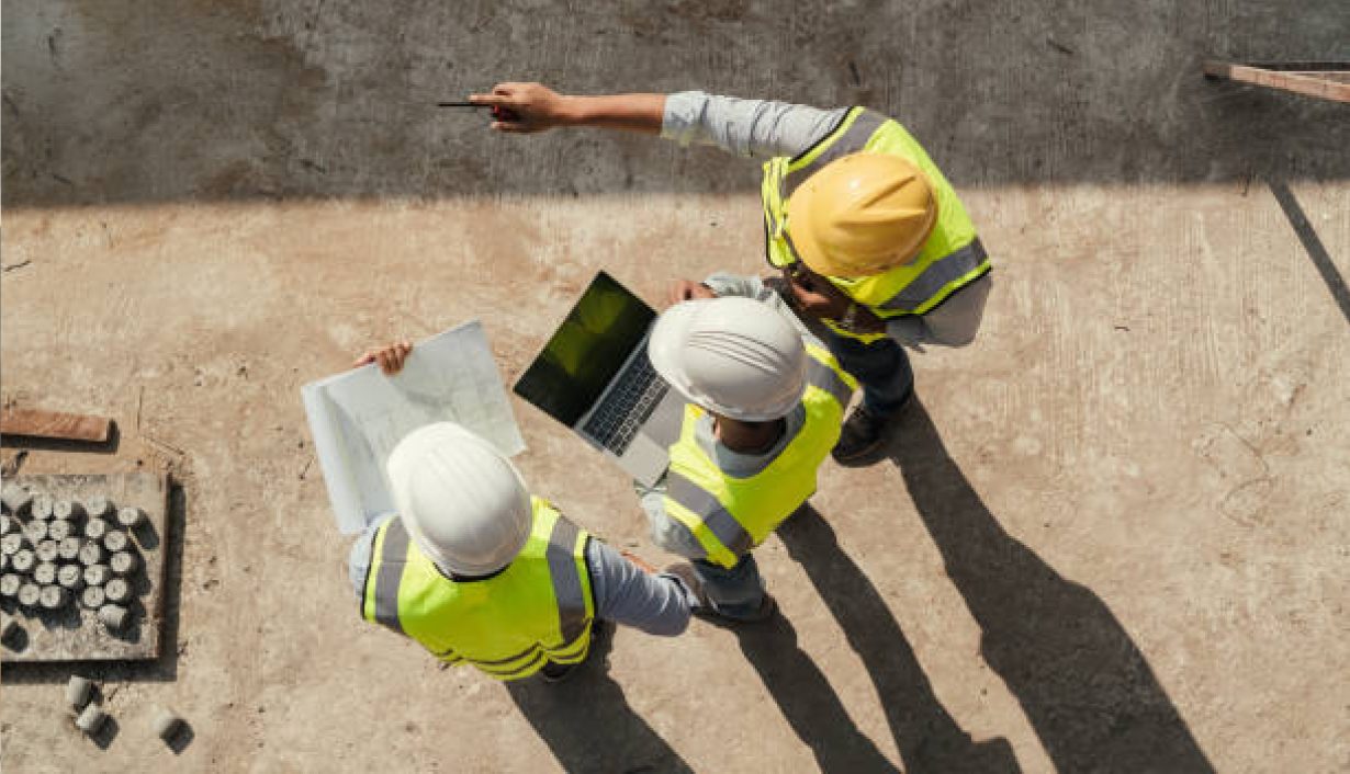 Engineers reviewing plans and a laptop on site