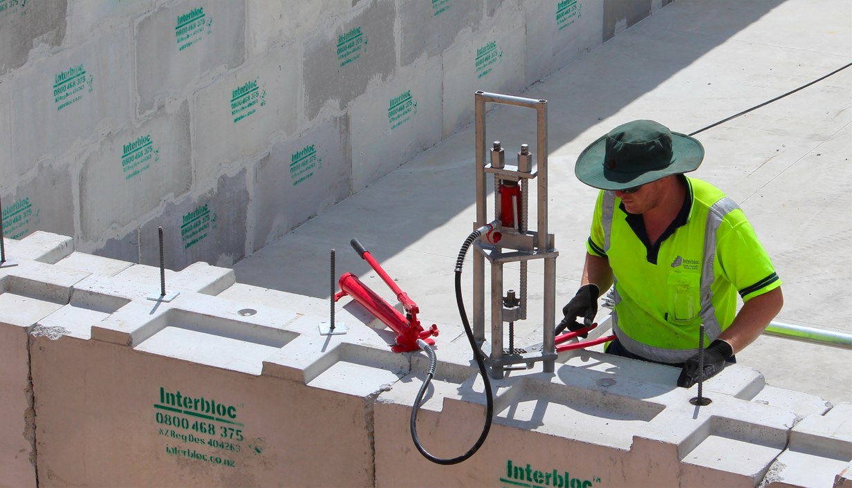 Installer using a hydraulic lifting tool to place an Interbloc block on a wall