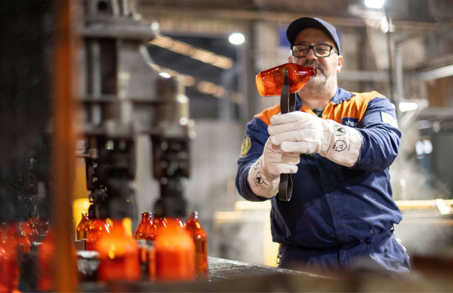 Visy Glass worker shaping molten amber glass at the Brisbane processing facility