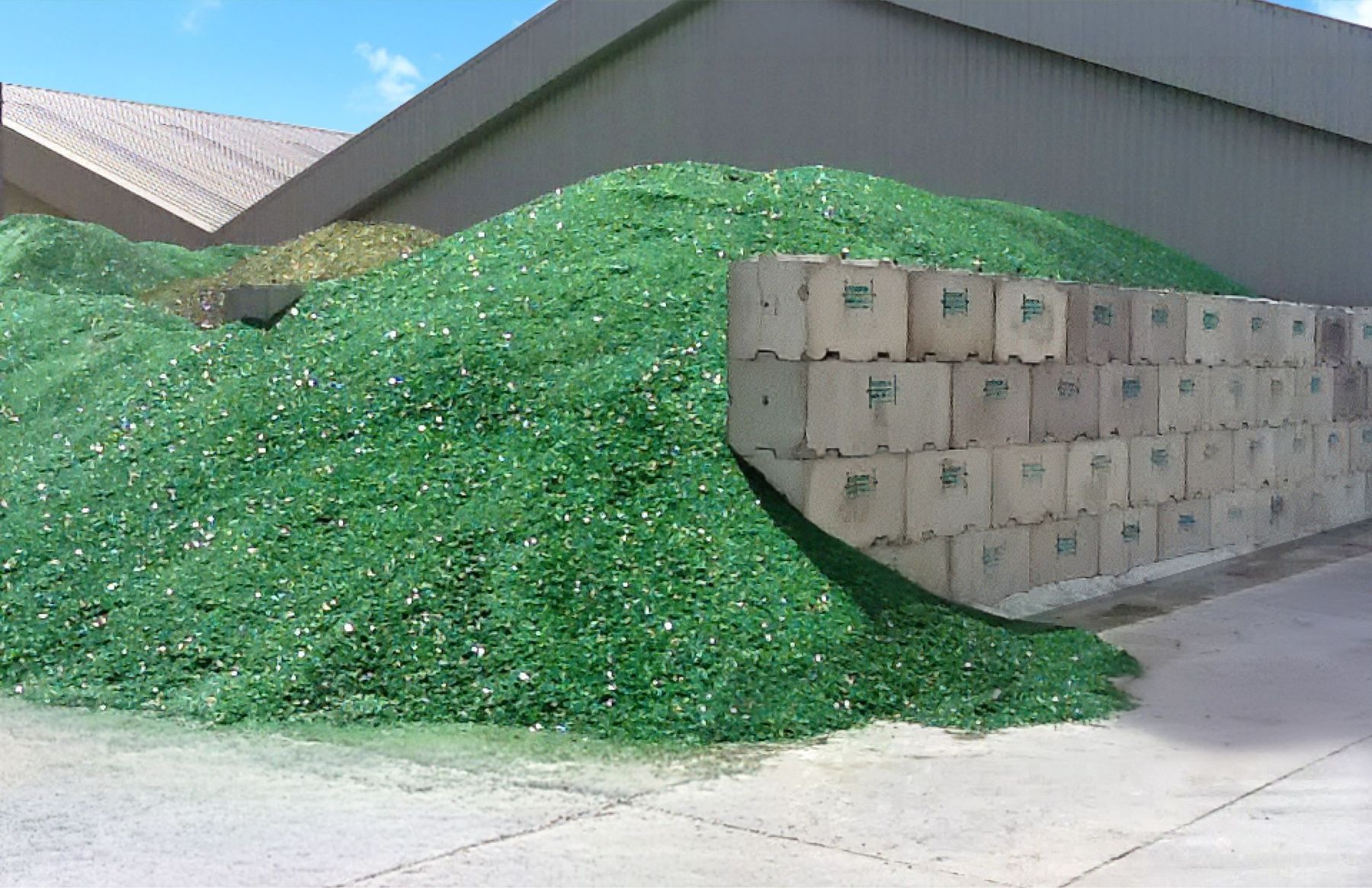 Crushed glass cullet stockpiled against an Interbloc retaining wall under a warehouse roof
